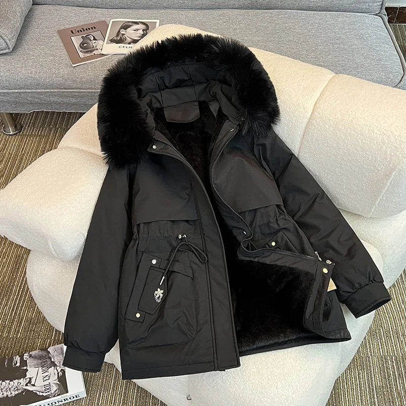 Black winter coat with fur-lined hood on a light-colored sofa.